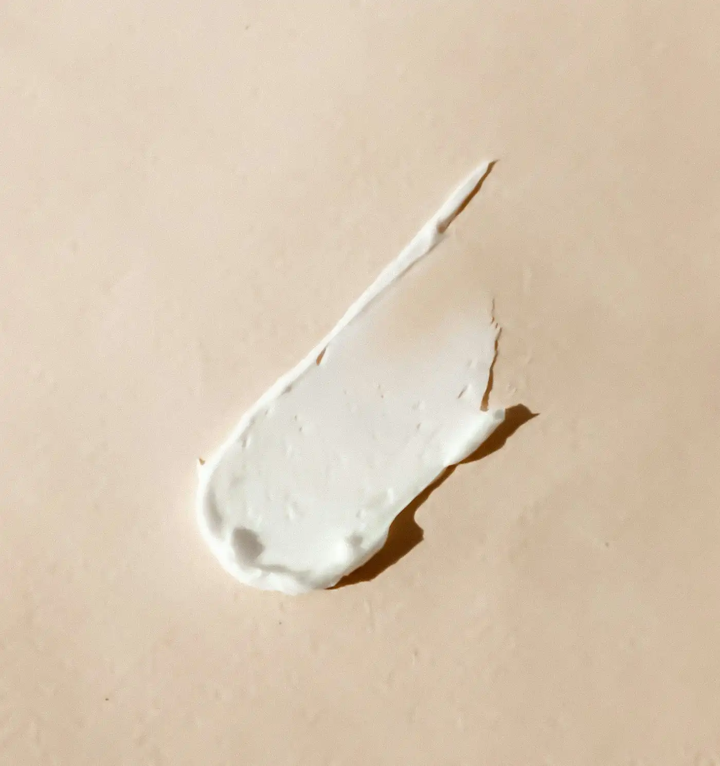 A swatch of thick white cream spread across a beige surface